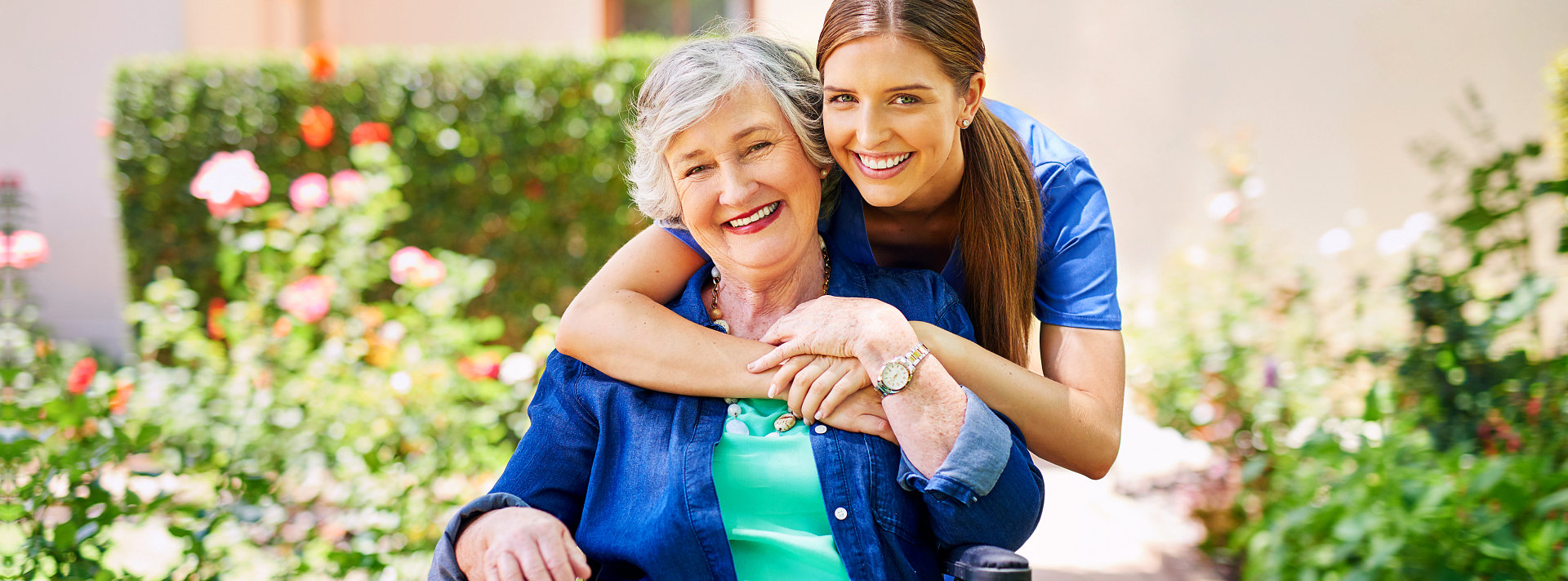 Elderly woman on wheelchair and her caregiver smiling