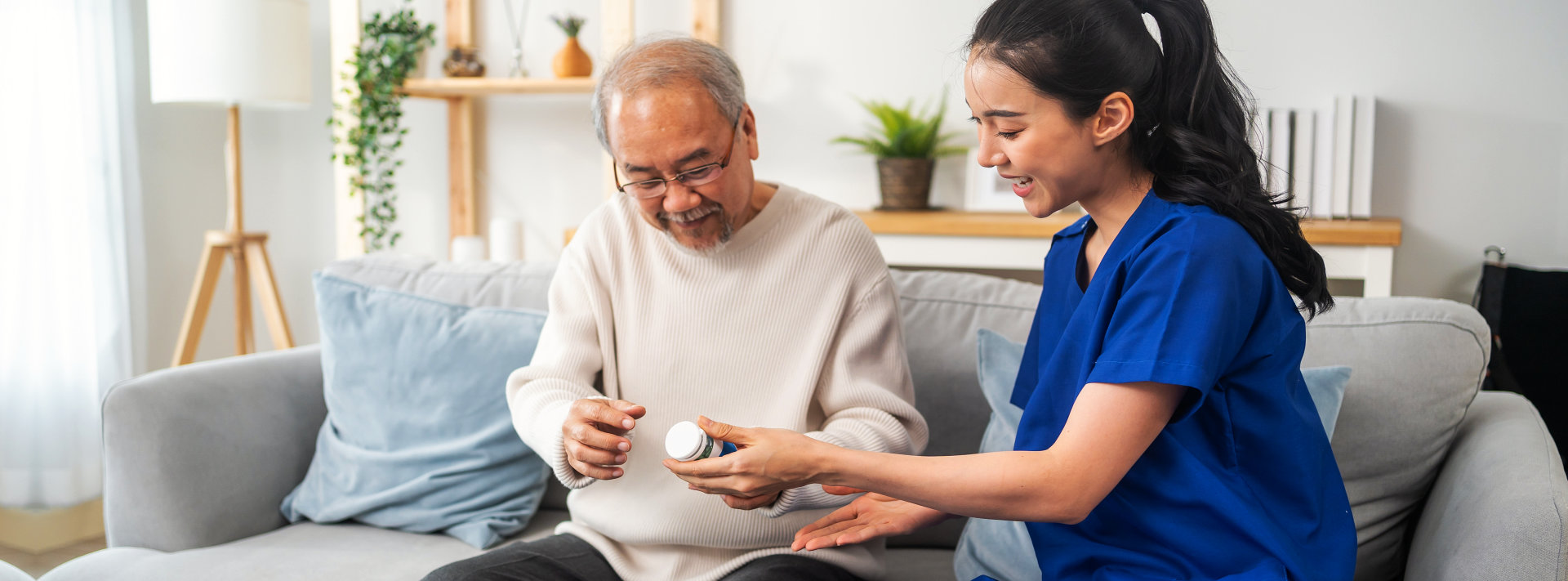 Caregiver giving a bottle of pills to an elderly man