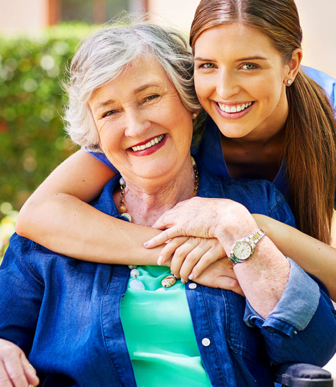 Elderly woman on wheelchair and her caregiver smiling