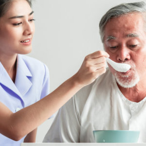 woman giving food to elderly man